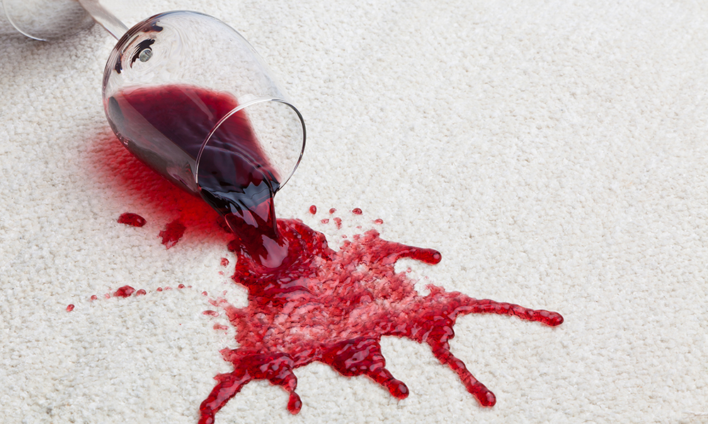 Glass of red wine spilled on white carpet
